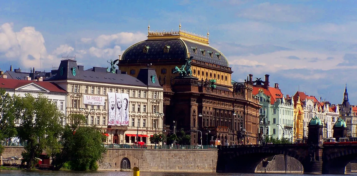 Nationaltheatret i Prag set over Vltava, med sin mørke kuppel kronet i guld ved Legionsbroen.